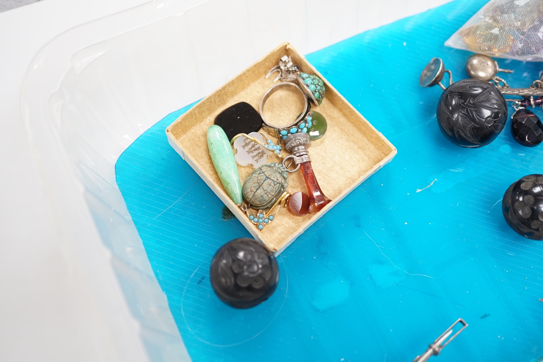 A silver charm bracelet hung with fifty assorted charms and a group of assorted jewellery including enamelled locket, Victorian agate fob seal carved with a bird, scarab pendant, coloured paste set brooch, 925 triple dol